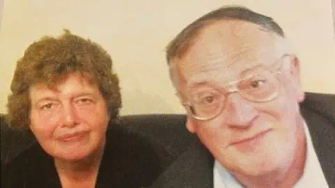 家庭资料：Lois and John McCullough。他们坐在沙发上，对着摄像头微笑。