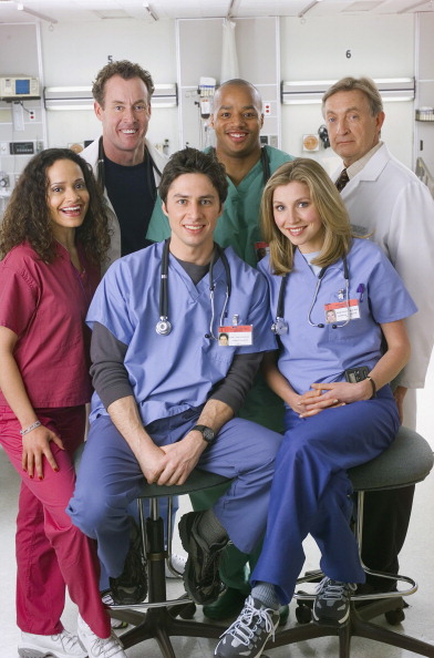The cast of Scrubs posing in a hospital set for promotional imagery